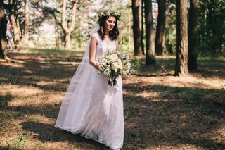 novia con vestido largo en el bosque con corona de flores y ramo