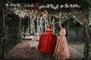 Mujeres con vestidos de fiesta en espacio decorado con flores y luces