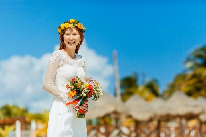 novia en la playa con ramo y corona de flores amarillas y rojas