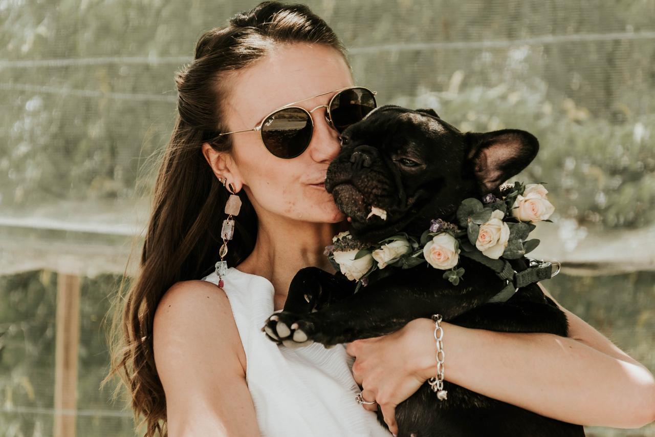 mujer abrazando a perro con corona de flores