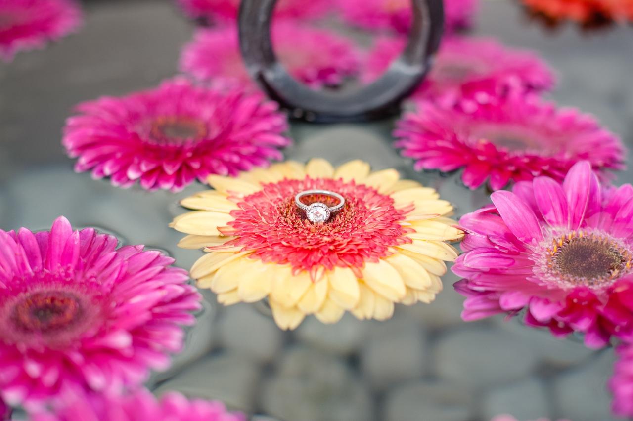 anillo de compromiso con diamante sobre flor amarilla y fucsia