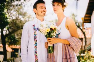 novio con guayabera bordada y novia con vestido sencillo y ramo de flores amarillas