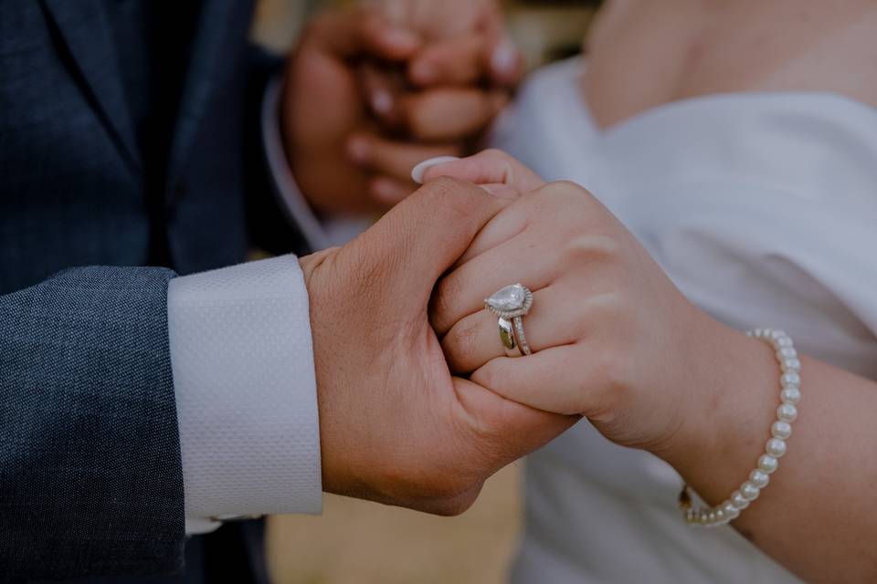 pareja de novios con manos entrelazadas mostrando anillo de compromiso