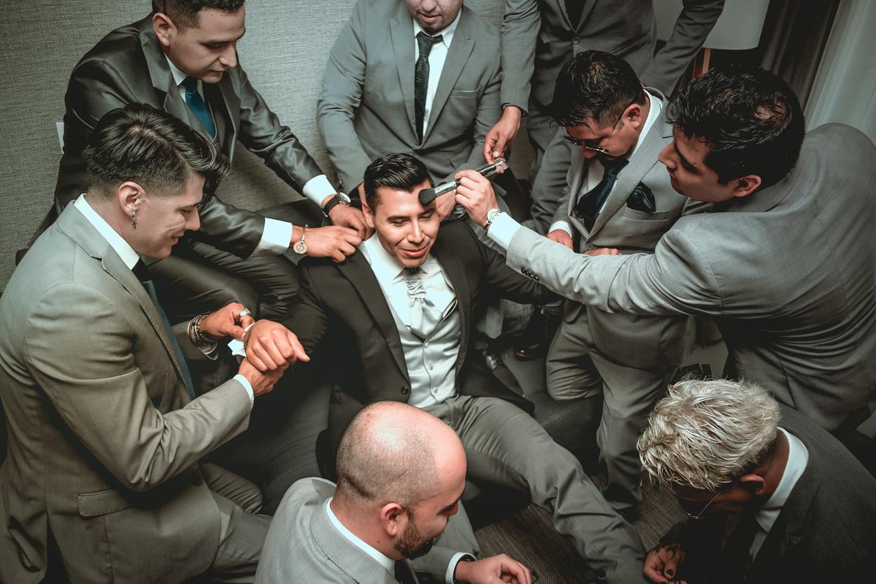 funciones de los damos de honor que acompañan relajan y maquillan al novio sentado en medio de ellos