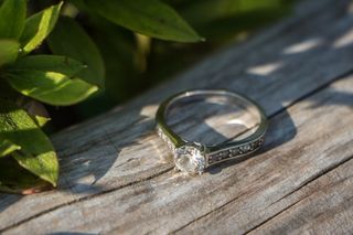 foto de anillo de compromiso solitario con diamantes en superficie de madera