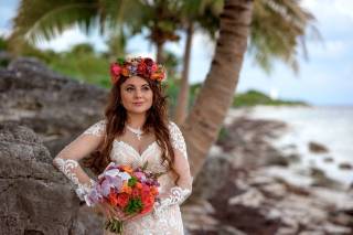 novia en la playa con vestido de manga larga ramo y corona de flores