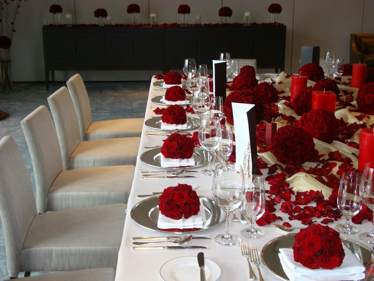 Arreglos florales elegantes con rosas rojas en mesa larga