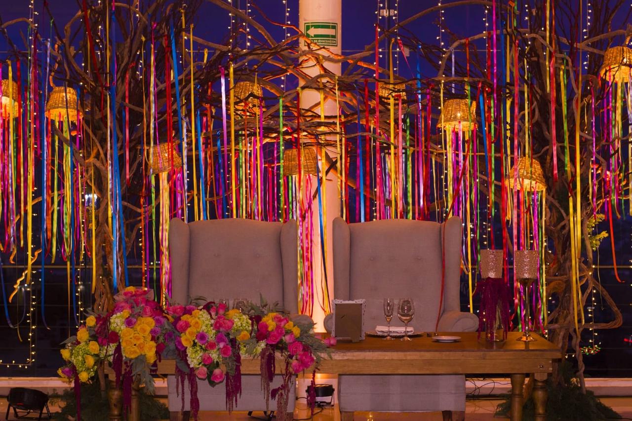 Mesa de novios decorada con listones y flores de colores a cargo de un profesional en decoración en Bodas.com.mx