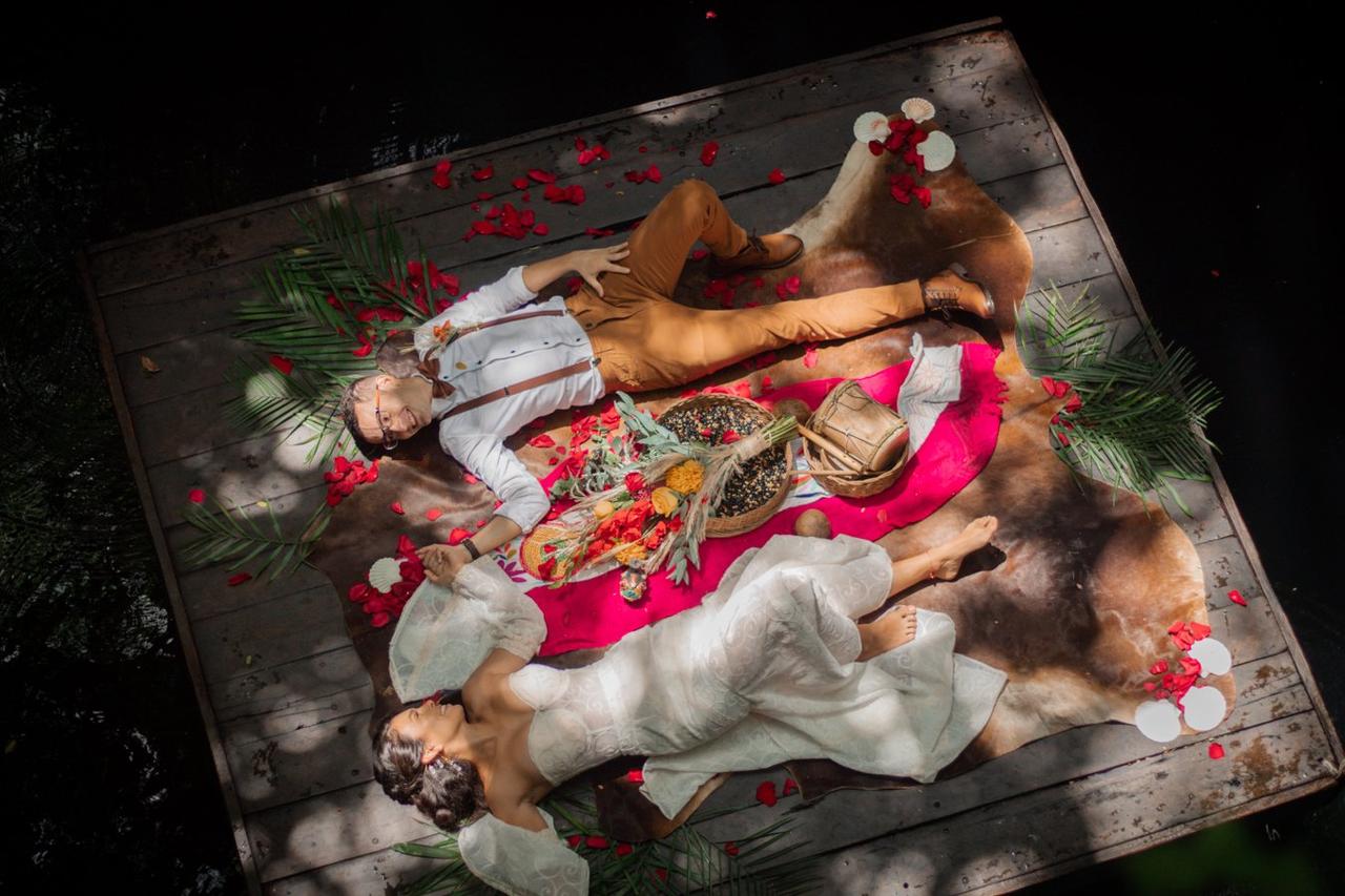 Novios acostados en una tarima de madera con flores, foto tomada por fotógrafo 