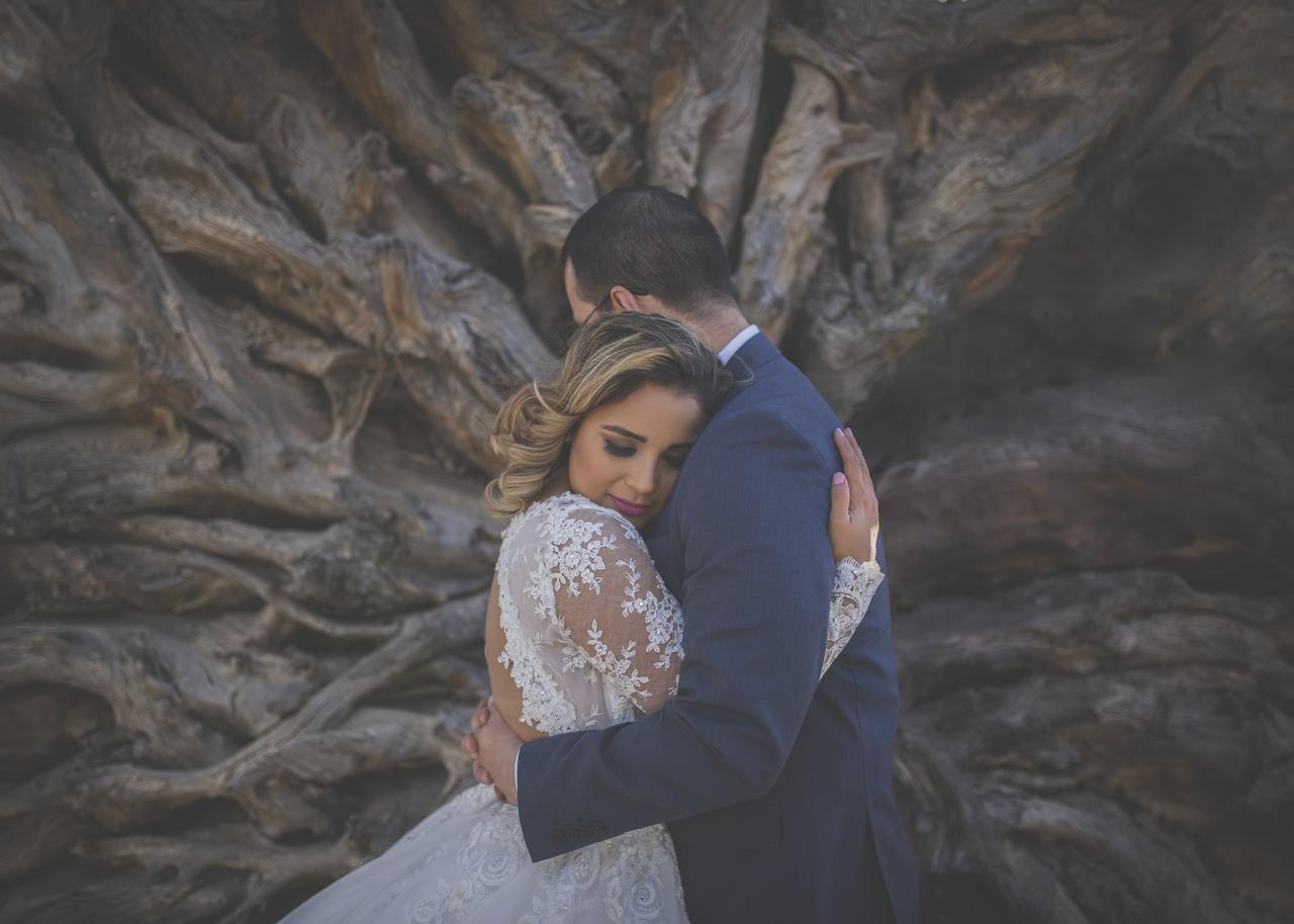 Novios abrazados frente a un árbol