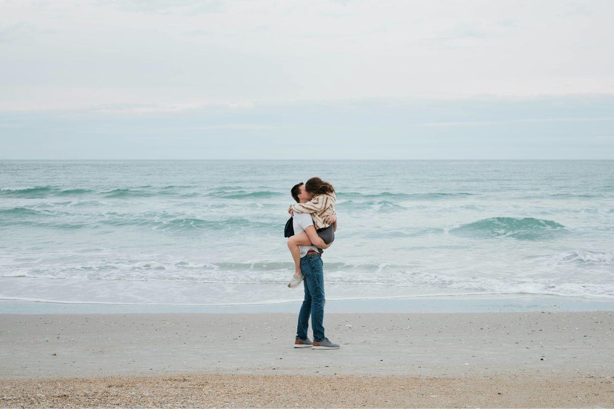 Pareja besándose frente al mar, ideal para comenzar un juego erótico en la playa