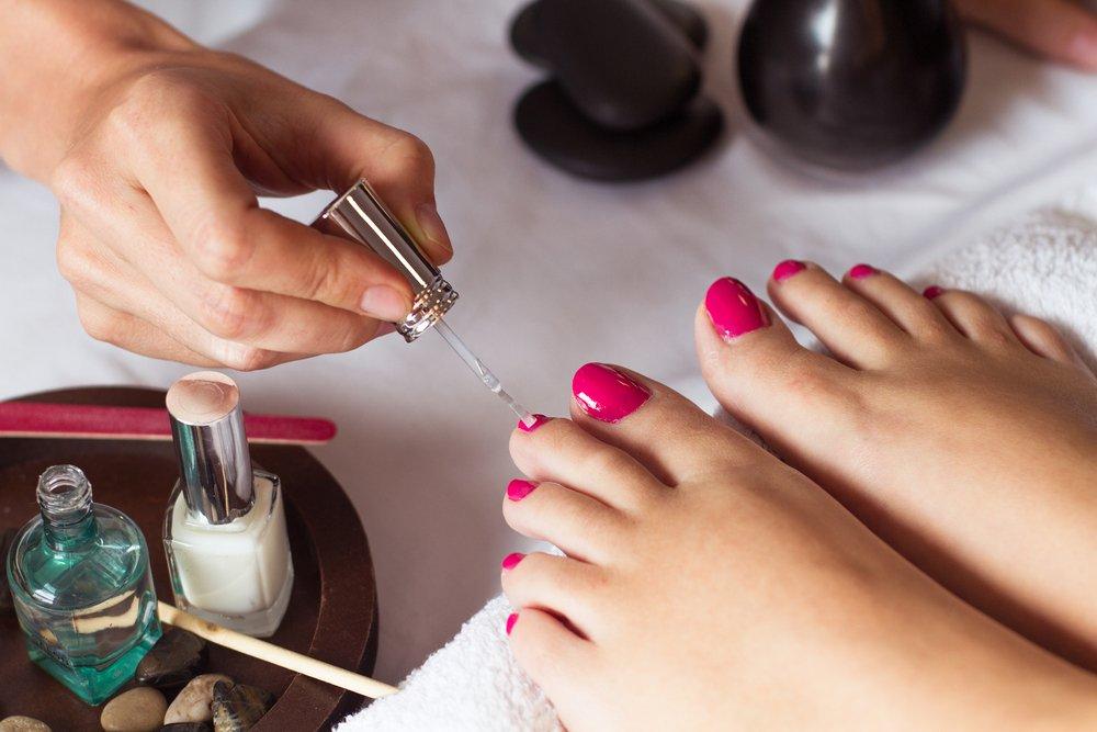 aplicación de esmalte rosa en uñas de pies