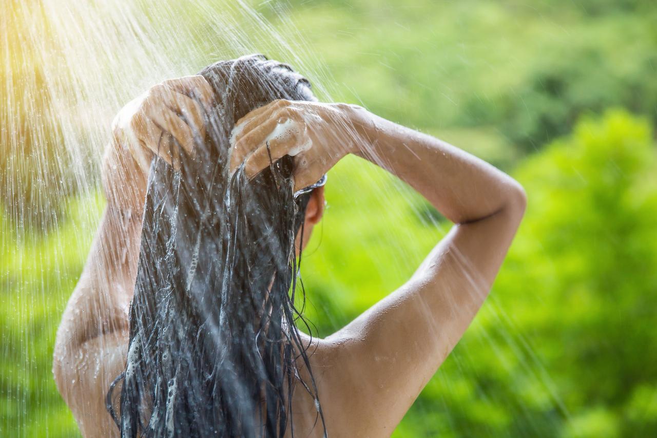 mujer lavándose el cabello de espaldas