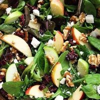 ensalada de espinacas, con manzana, arándano, nuez, almendras y queso de cabra