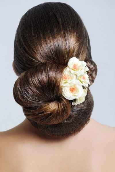 Recogido abundante enroscado con tocado de flores.