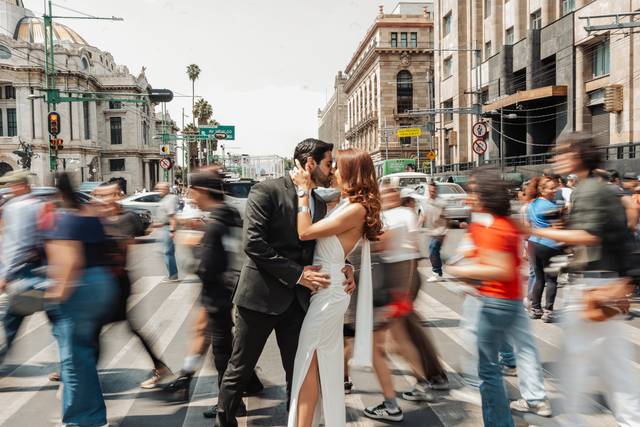 Novios besándose en medio de la calle con las personas de fondo