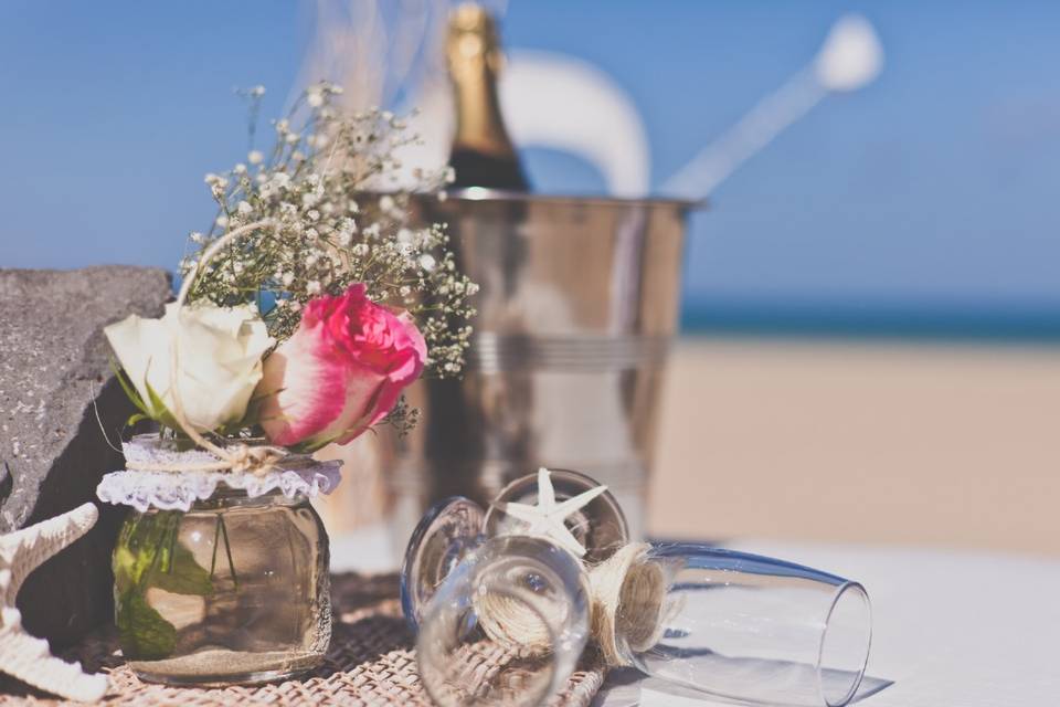 Decoración en la playa con flores y botella