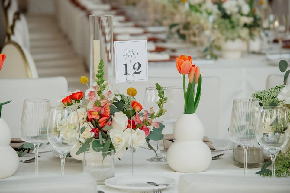 Mesa con número, flores naranjas y copas de cristal