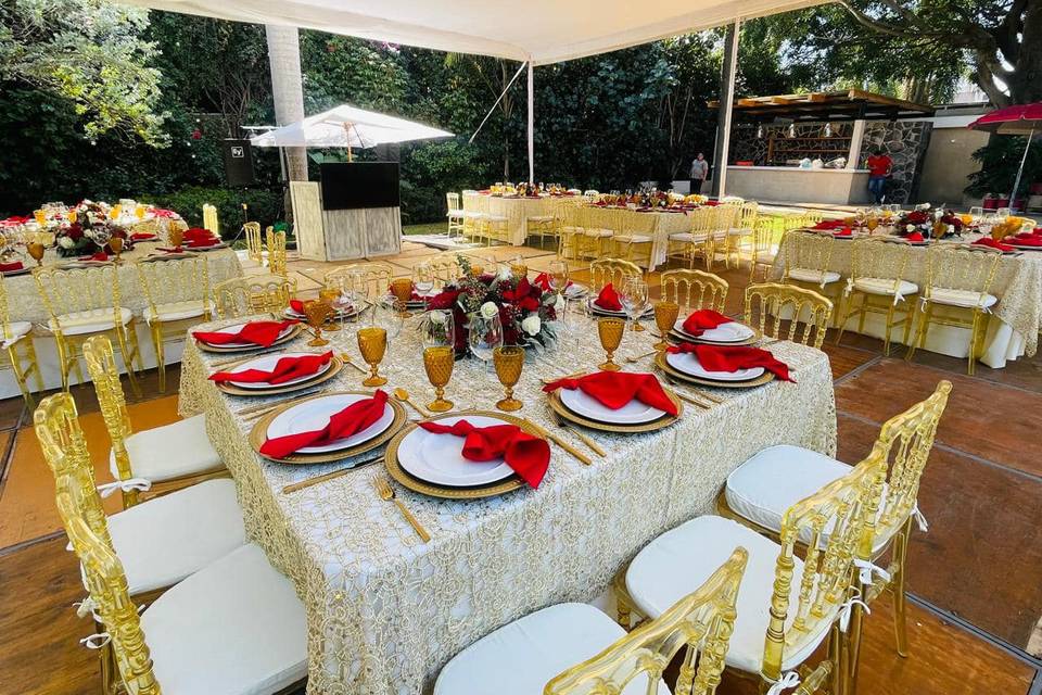 Mesa cuadrada con manteles dorados y servilletas rojas