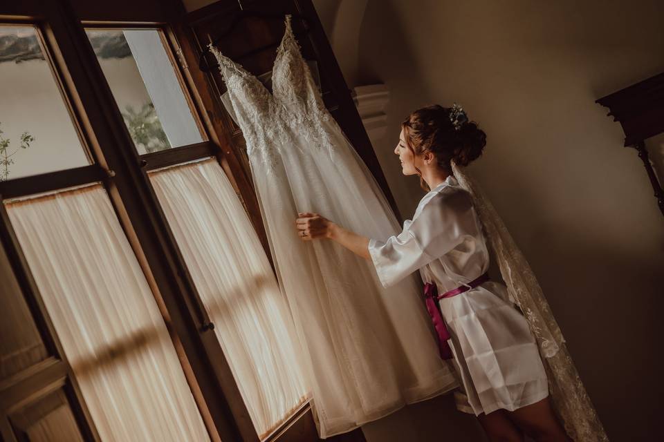 Novia mirando su vestido colgado en la ventana