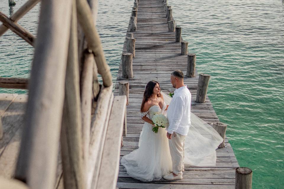 Pareja posando en un puente de madera en la playa