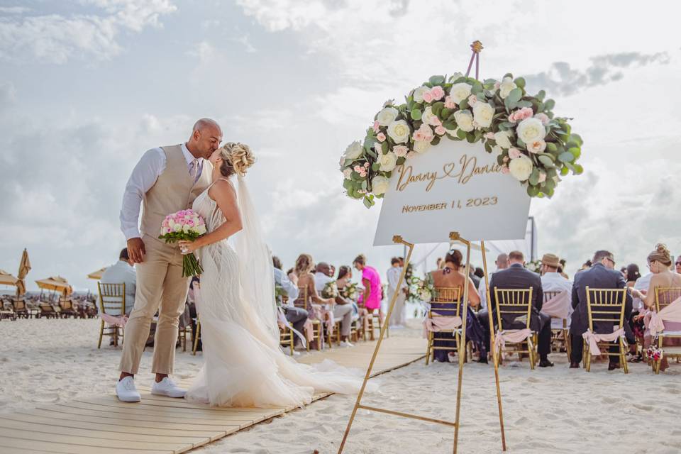 Novios besándose en el pasillo al altar en la playa