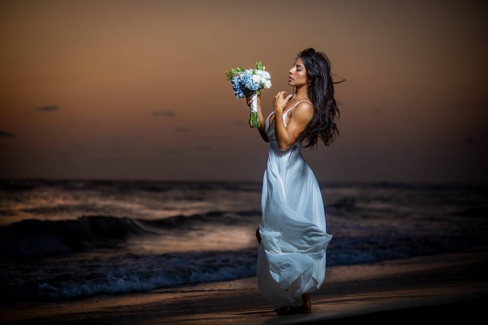 Novia sosteniendo su ramo en la playa