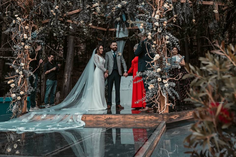 Novios casándose bajo una estructura de flores