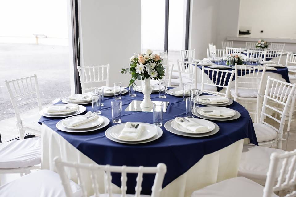 Loza blanca en mesa redonda con mantel azul