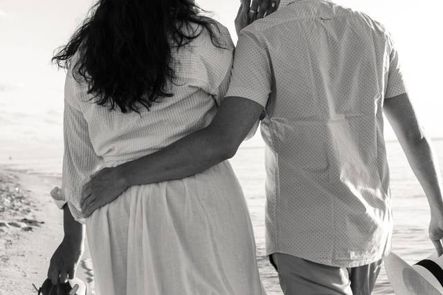 Pareja abrazada y descalza en la playa
