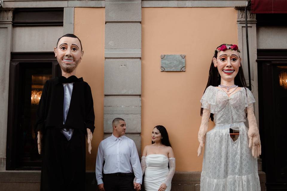 Novios recargados en la pared con mojigangas