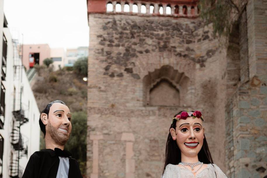 Novios besándose acompañados de mojigangas