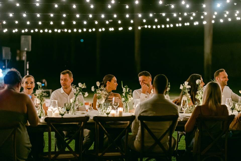 Invitados en la mesa decorada con luces y flores blancas