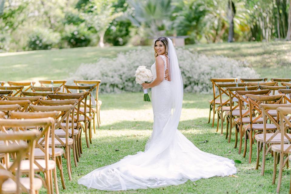 Novia en el pasillo al altar sosteniendo un ramo de flores blancas