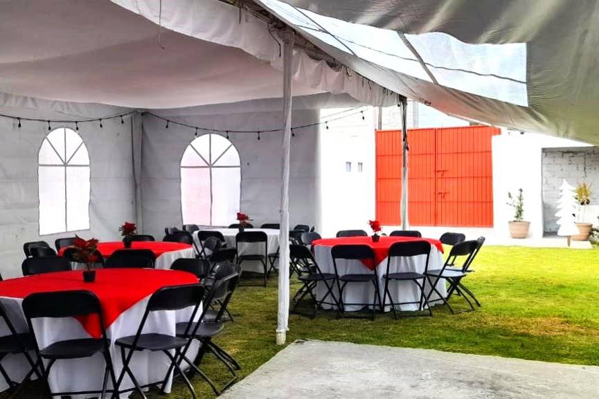 Jardín con mesas redondas y sillas negras con una carpa