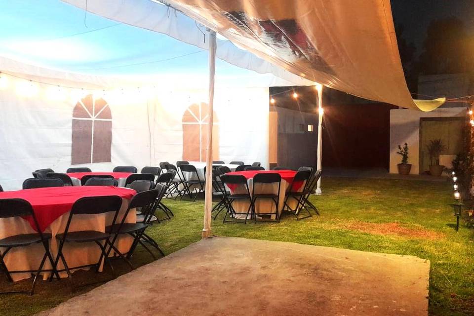 Carpa blanca, sillas y mesas en un jardín