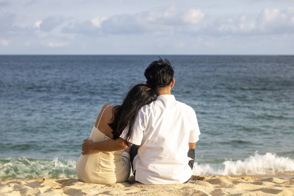 Pareja sentada en la arena frente al mar