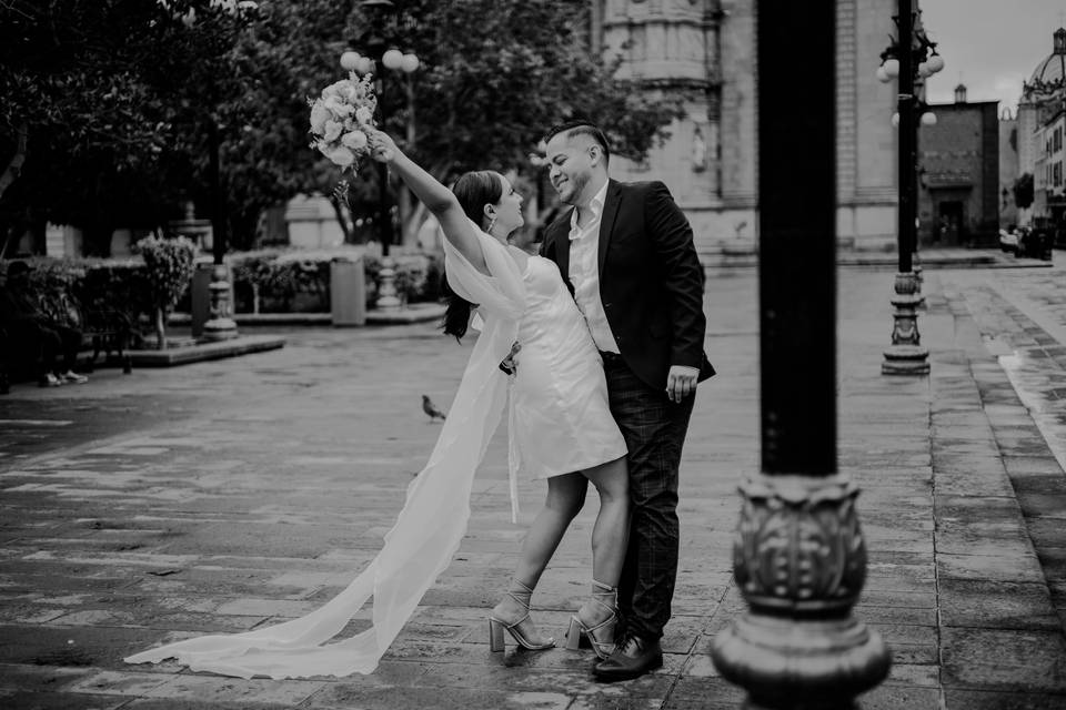 Novios posando a lado de un poste