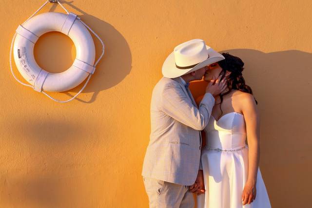 Novios dándose un beso recargados en una pared