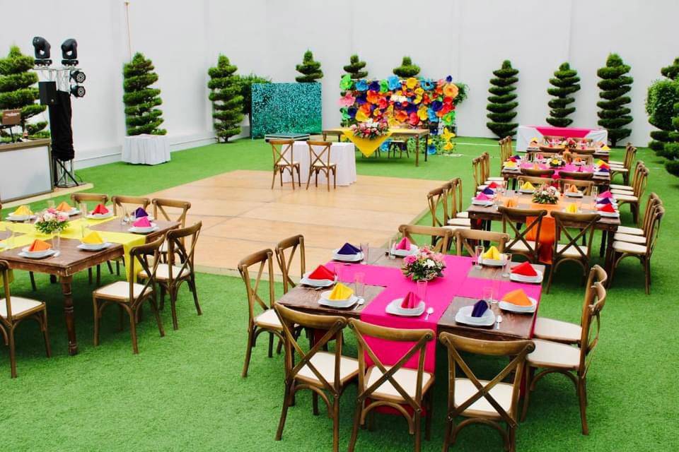 Jardín con mesas de madera y servillas de colores