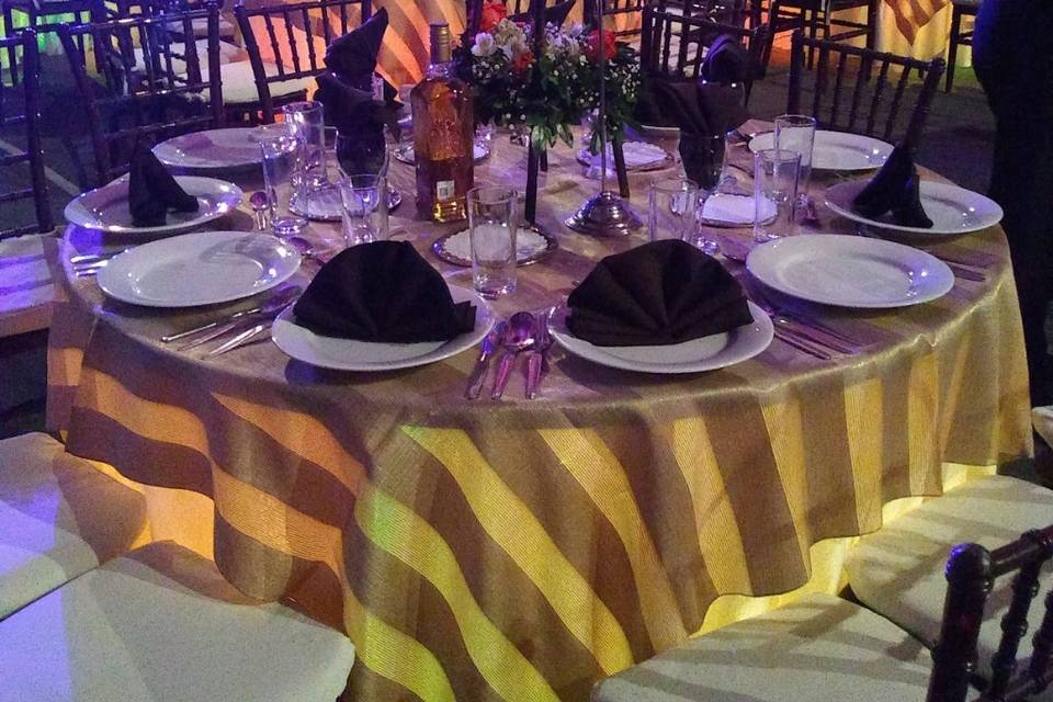 Mesa con mantel dorado y vajilla blanca