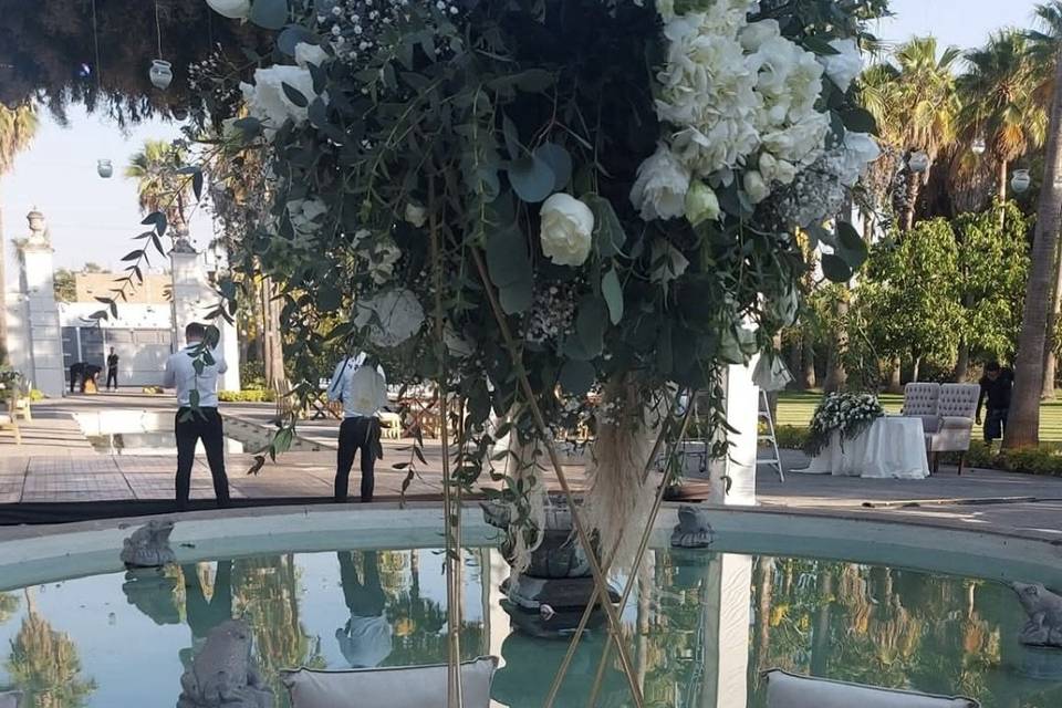 Mesa redonda decorada con vajilla blanca y florero alto