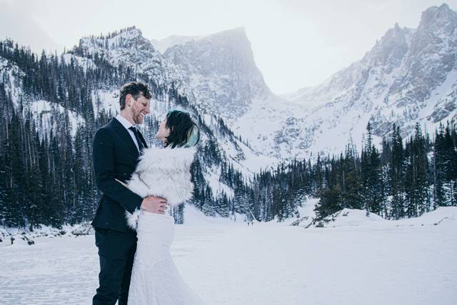 Pareja mirándose a los ojos y sonriendo en medio de la nieve