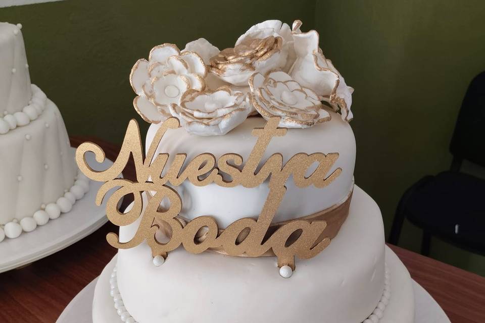 Pastel blanco con dorado y flores encima