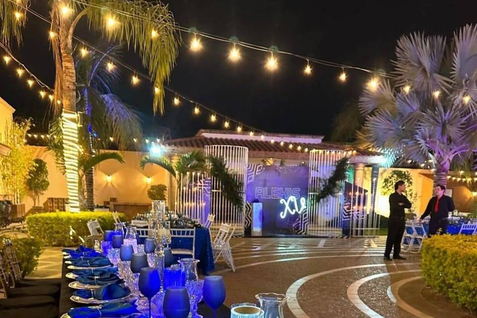 Mesa montada con platos blancos y plateados y copas azules