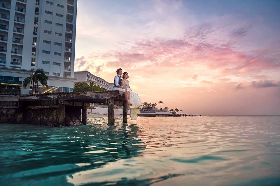 Pareja viendo el atardecer sentados en el muelle