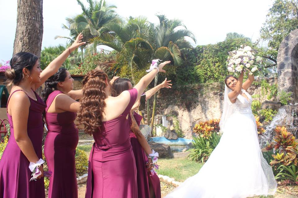 Novia con su ramo y damas de honor en un jardín