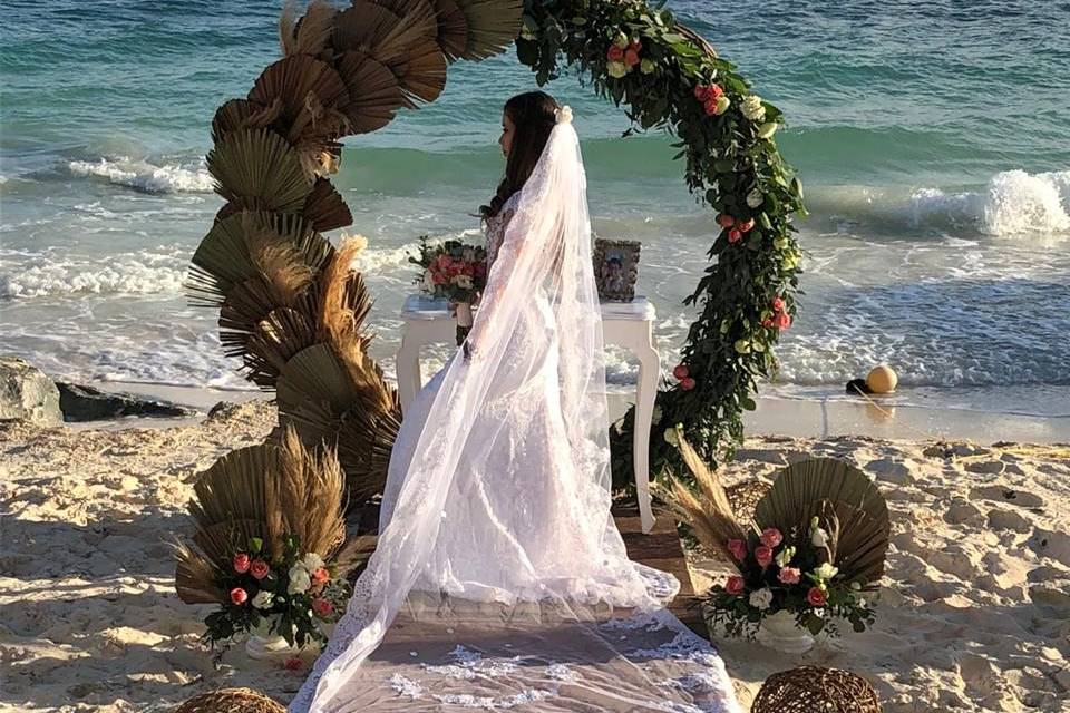 Novia frente a un arco de flores en la playa