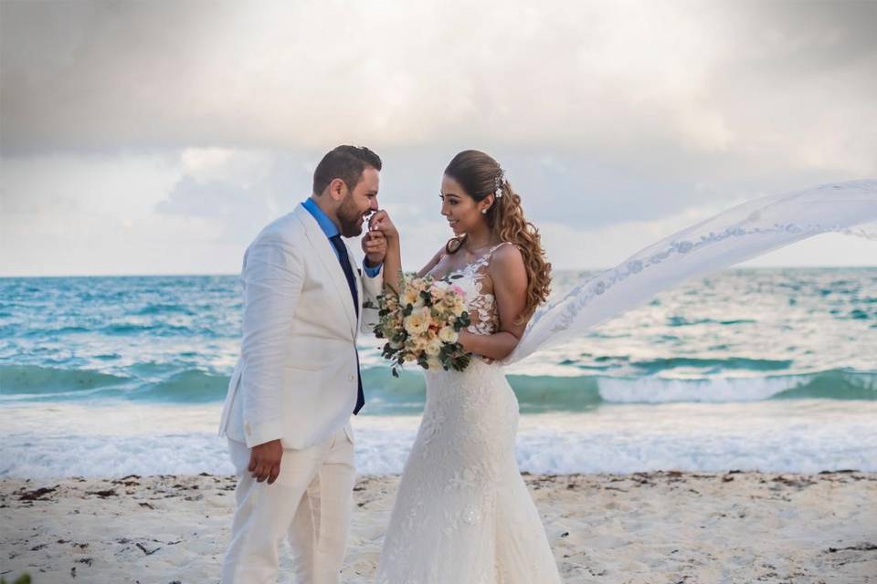 Novio besándole la mano a la novia en la playa