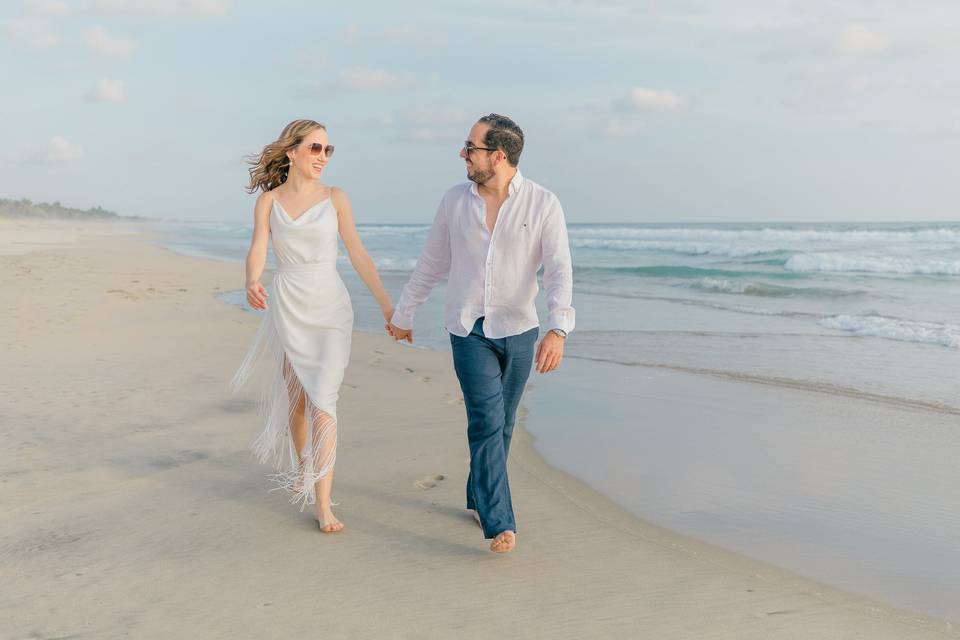 Pareja agarrados de la mano caminando por la playa